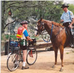 Photo horse mounted U.S. Park Police Officer speaking with bike patrol volunteer.