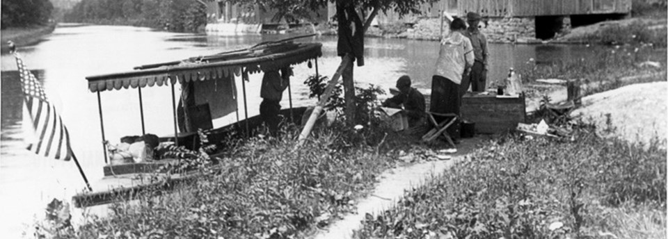 Historic photo of picnickers eating off the side of a canal boat