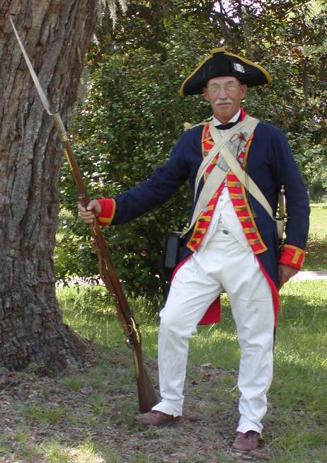 Costumed interpreter in Revolutionary War uniform with musket.