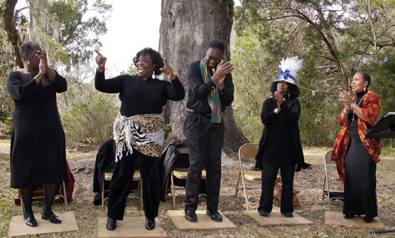 Five African Americans performing a cultural song and dance beneath a Live Oak tree.