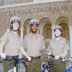 Park rangers with bicycles pose in front of Little Rock Central High School.