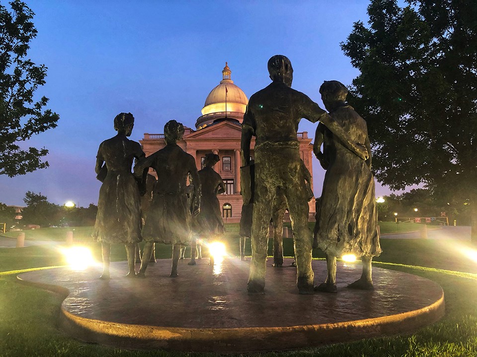 Statues of the Little Rock Nine face the Arkansas State Capitol at dusk