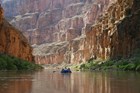 Photo of a raft floating on river in a steep narrow canyon.