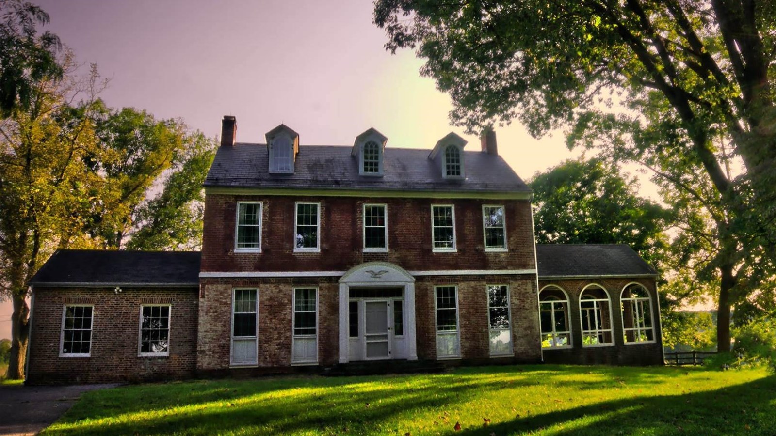 A two-story, brick farm house with dormer windows.