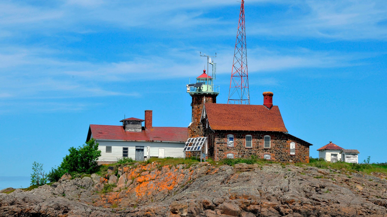 lighthouse, communication tower, and garage structure on a rocky island