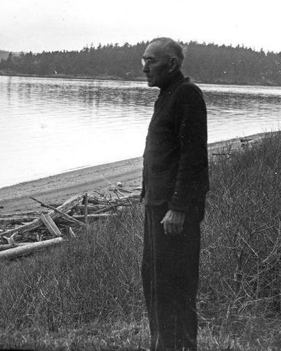 Black and white photo of an elderly man looking across a beach