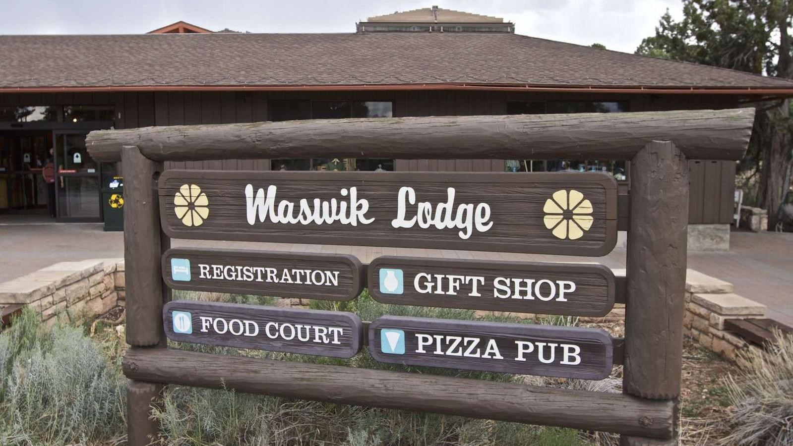 Wooden sign in front of single story lodge building reads Maswik Lodge, Registration, Gift Shop etc.