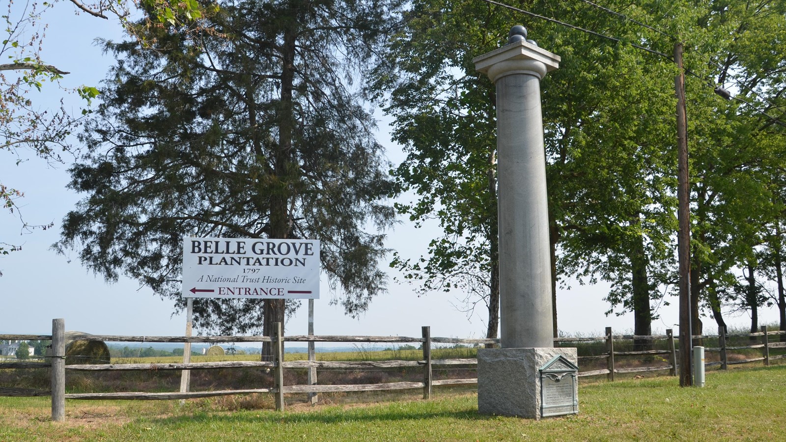 A stone pillar war memorial stands at a country road intersection. 