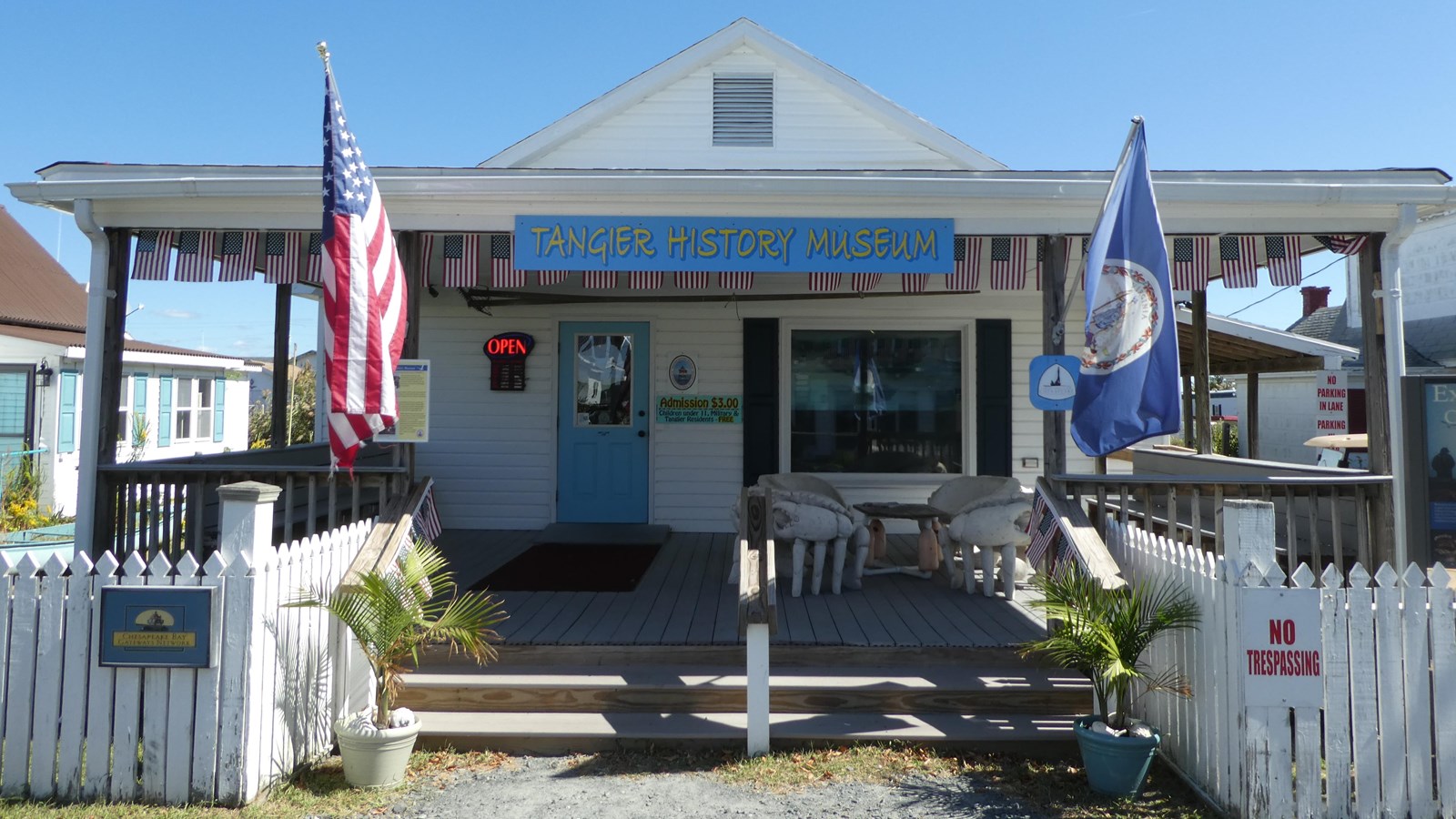 A small museum front with blue door, flags, and signs for NPS affiliation. 