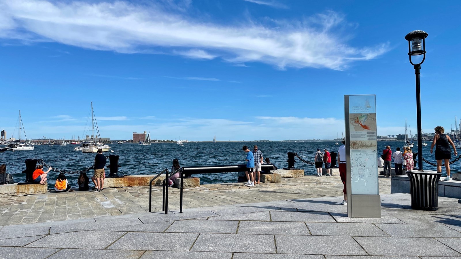 The edge of a wharf overlooking the harbor. Benches and big black dividers with chains line the edge