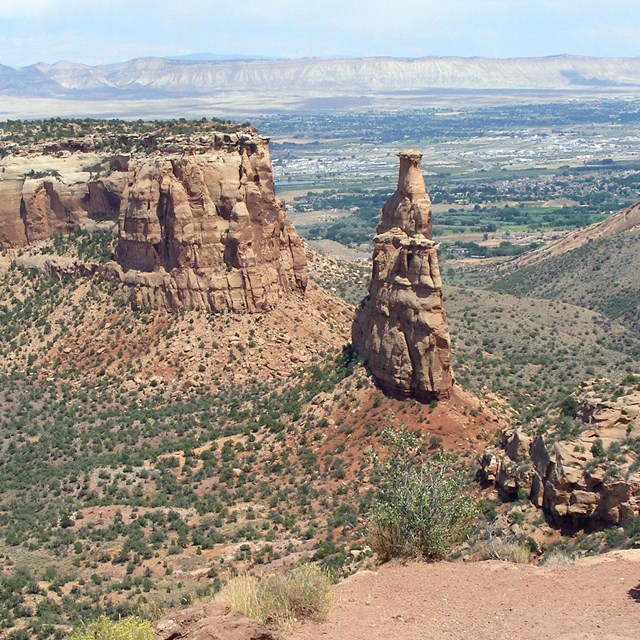 Independence Monument sandstone rock formation with the Grand Valley beyond. 