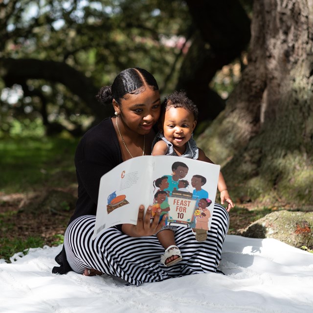 A mother reads to her baby under the Emancipation Oak tree in Hampton, Virginia