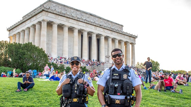 Two law enforcement rangers in front of a memorial