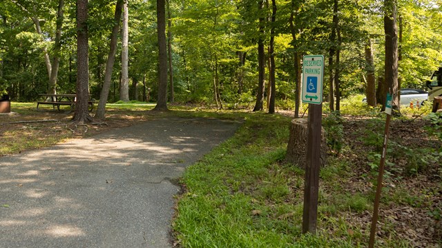 A handicapped parking sign near a paved trail.