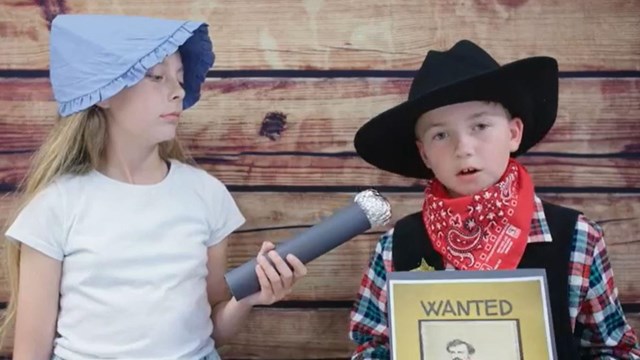 kids dressed up, one pretending to be interviewing the other dressed as sheriff  