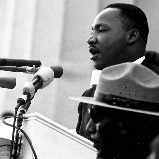 Martin Luther King stands in front of microphones