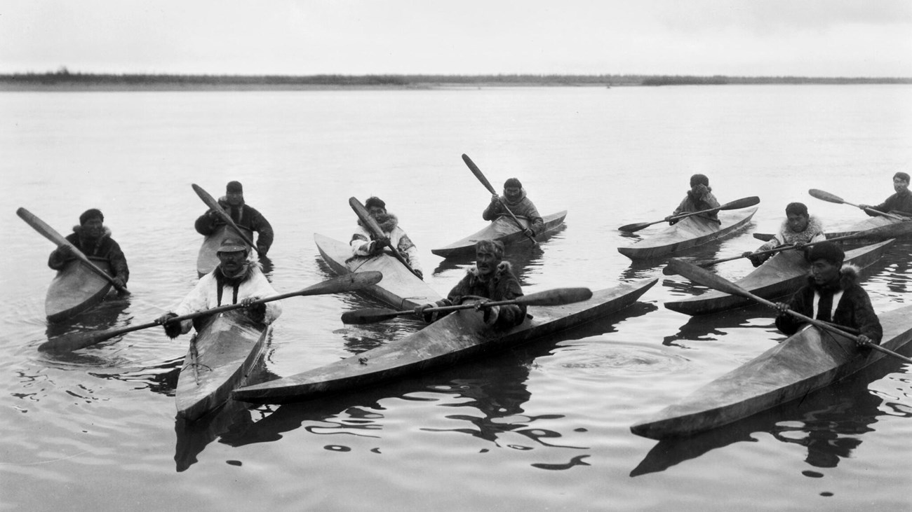 Balck and white photo of people in kayaks on the water.