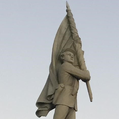 soldier on top of a monument carrying a flag