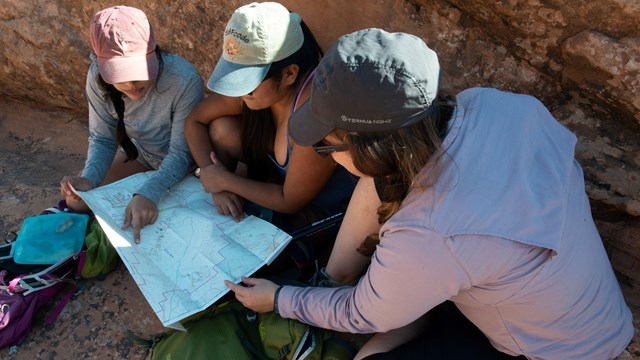 Three hikers look at a map to see where they're headed next