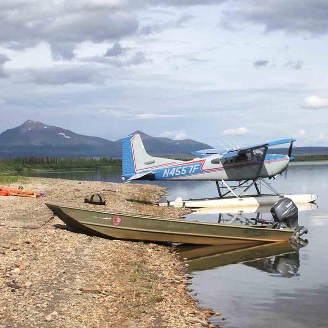 A float plane and boat pull onto the shore of the Kobuk River.