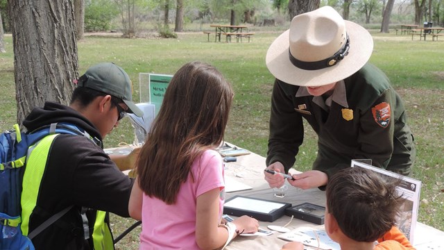 Ranger and kids examine pottery sherds.