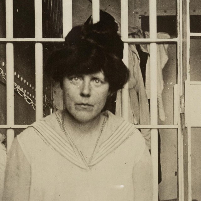 Lucy Burns seated outside a jail cell door