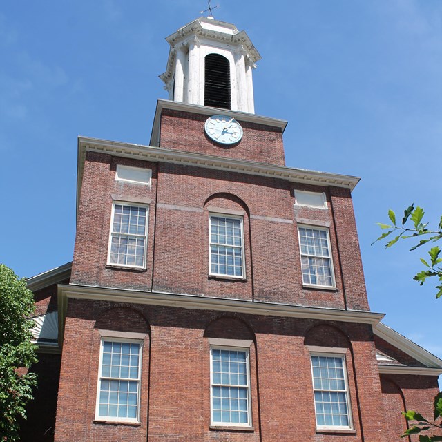 Three story brick building with white bell tower