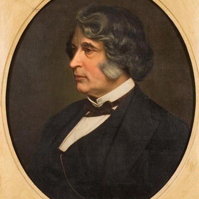 side portrait of Charles Sumner with short wavy hair tinged with gray and a dark suit.