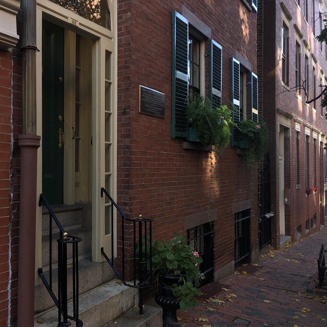 Diagonal view of shaded street of Beacon Hill with townhouses and a partial view of the sidewalk.