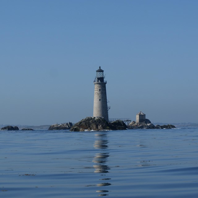 A rocky outcropping with a lone lighthouse.