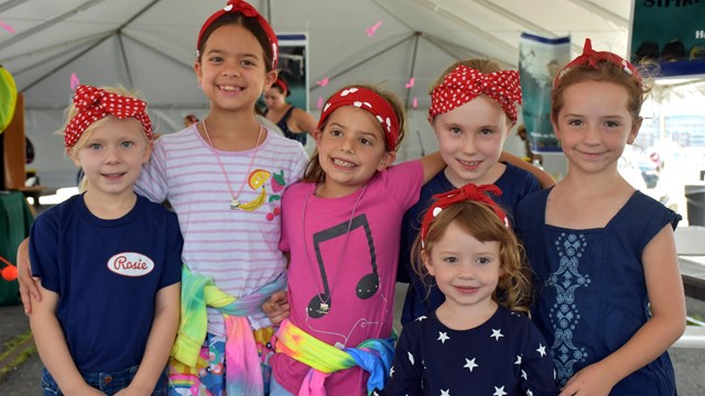 group of small girls wearing Rosie the Riveter red bandanas.