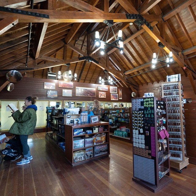 The interior of a wooden building with store displays under chandeliers.