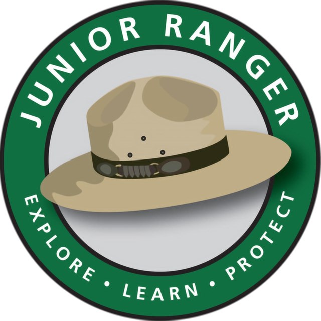 Cartoon ranger hat over green circle that reads Junior Ranger, Explore, Learn, Protect