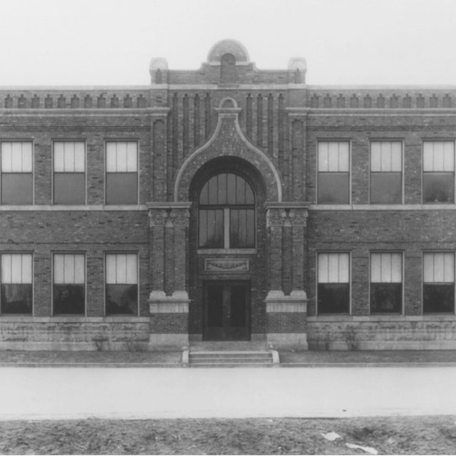 black and white image of brick building with arched entrance