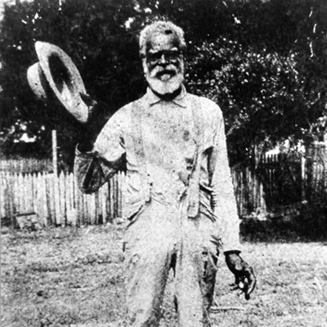 Minique Toussant stands holding his hat at Oakland Plantation. 