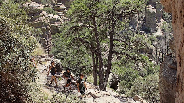 A hiker pauses under rock formations