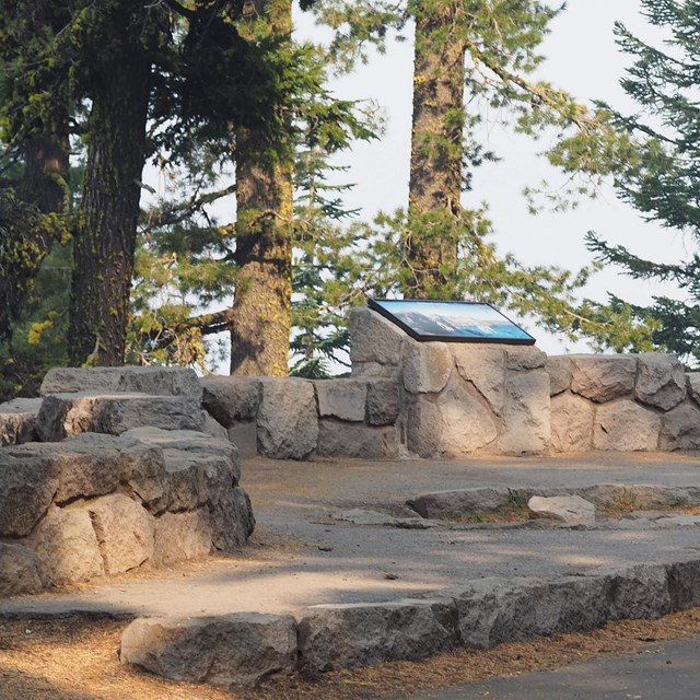 An information exhibit is set in a circular stone wall overlooking Crater Lake.