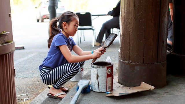 Child volunteer painting a structure