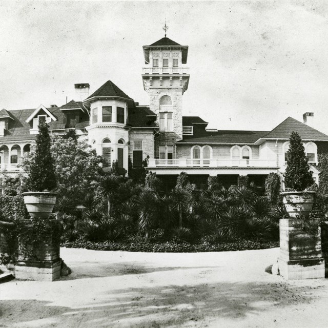 view of large mansion with tower and gardens