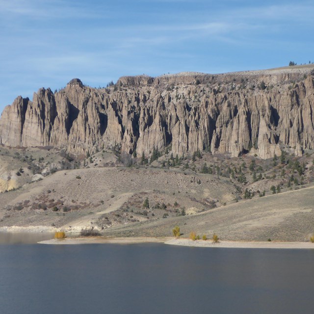 Rocky pinnacles and desert hillsides rise above a lake in the foreground