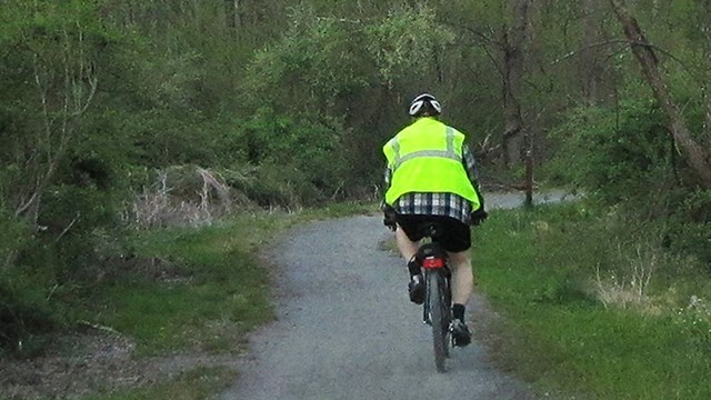 A DEWA volunteer on a bike wearing a helment and their volunteer uniform.