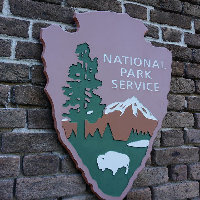the national park service arrowhead logo on a brick wall