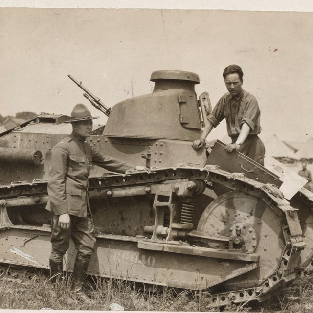 Two men pose with a WWI era tank on the Gettysburg battlefield.