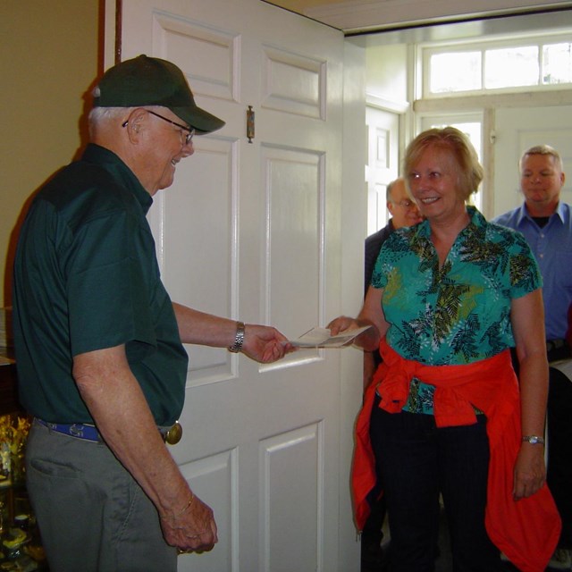 A volunteer holds the front door open for a group of visitors ready to tour the Eisenhower home. 