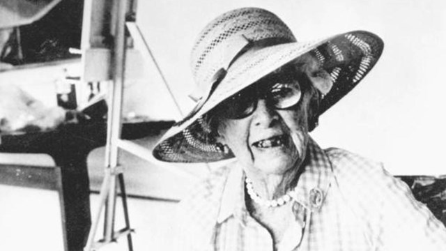 Marjory Stoneman Douglas sitting in a chair and is holding a book. 
