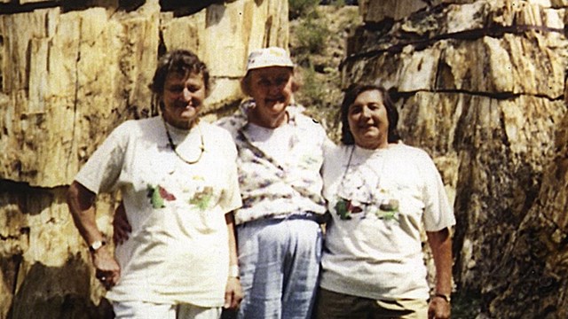 three women stand in front of a petrified trio redwood tree