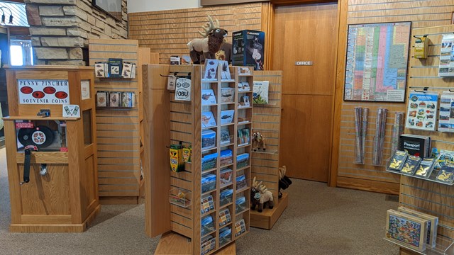A bookstore with various merchandise, a penny press, and a fossil with lots of fish hanging above.