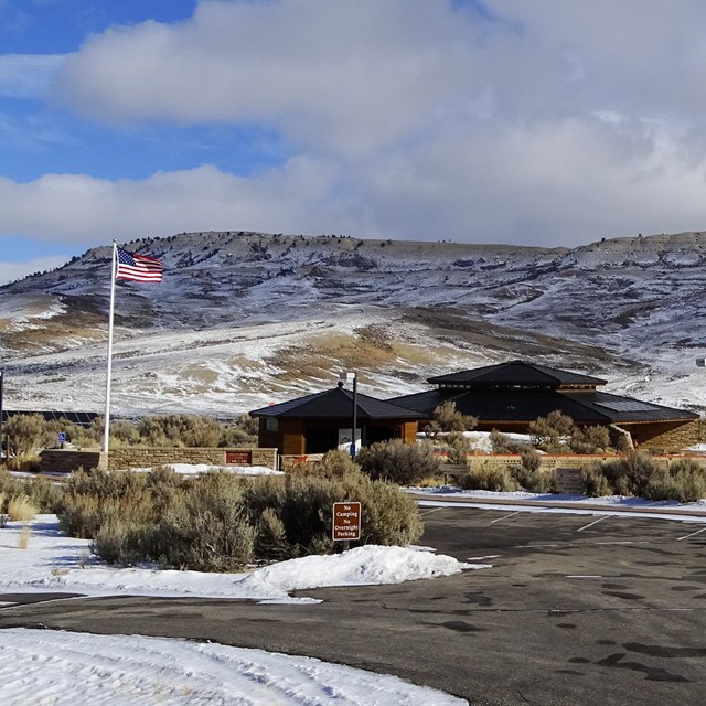 The visitor center in front of partially snow-covered Fossil Butte. The flag is flying in front.