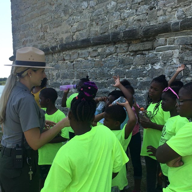 Ranger with a group of kids outside the fort. 