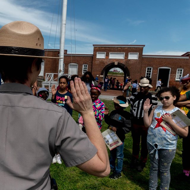 An image of a park ranger swearing in a group of junior rangers.